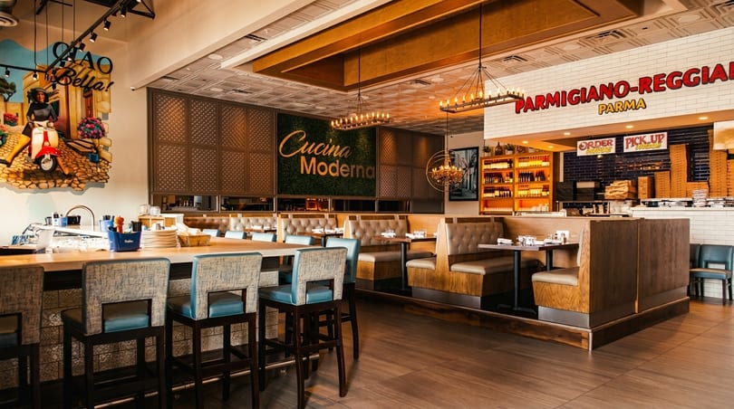 Spacious Italian restaurant interior with a long bar, booths, and a "Cucina Moderna" sign.